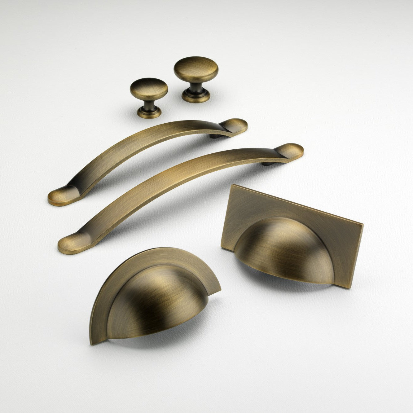 Monmouth antique brass cabinet handle collection with cup handles, bow handles and knobs