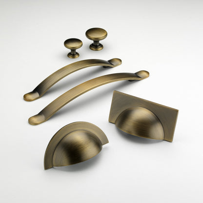 Monmouth antique brass cabinet handle collection with cup handles, bow handles and knobs